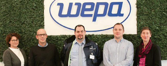 WEPA-Team und Piepenbrock Mitarbeiter vor grüner Wand mit wepa-Logo in der Mitte
