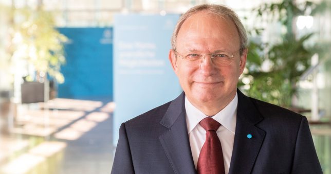 „In einer automatisierten Produktion spielt die Instandhaltung eine zentrale Rolle“ Portraitbild Dr. Ing. Jens Reichel mit blauem Anzug und roter Krawatte