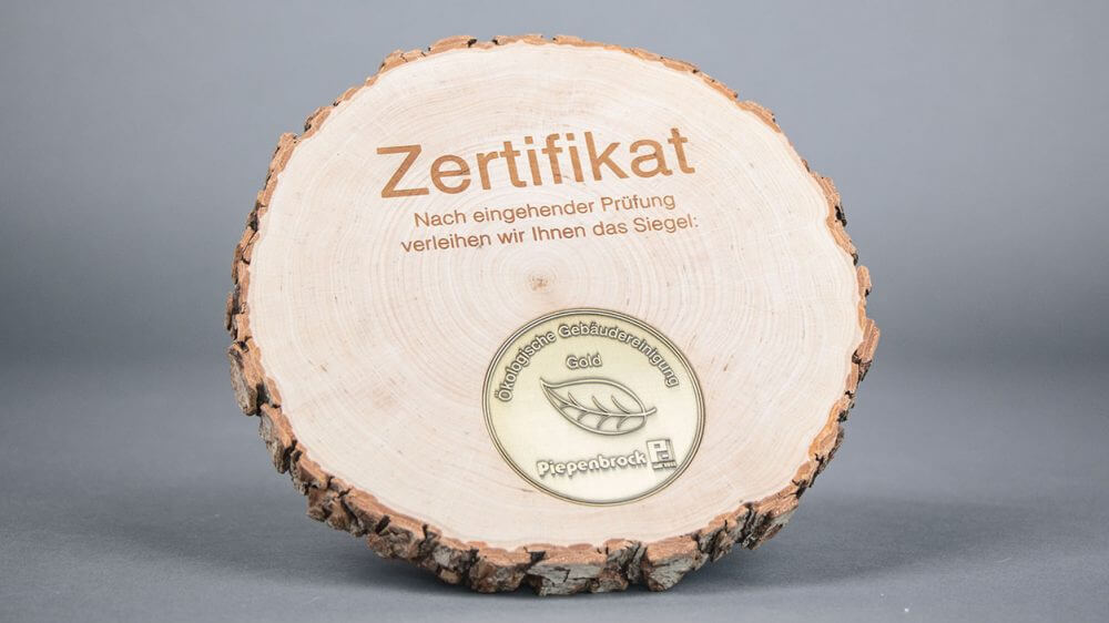 Ein Siegel "Ökologische Gebäudereinigung" in Gold.