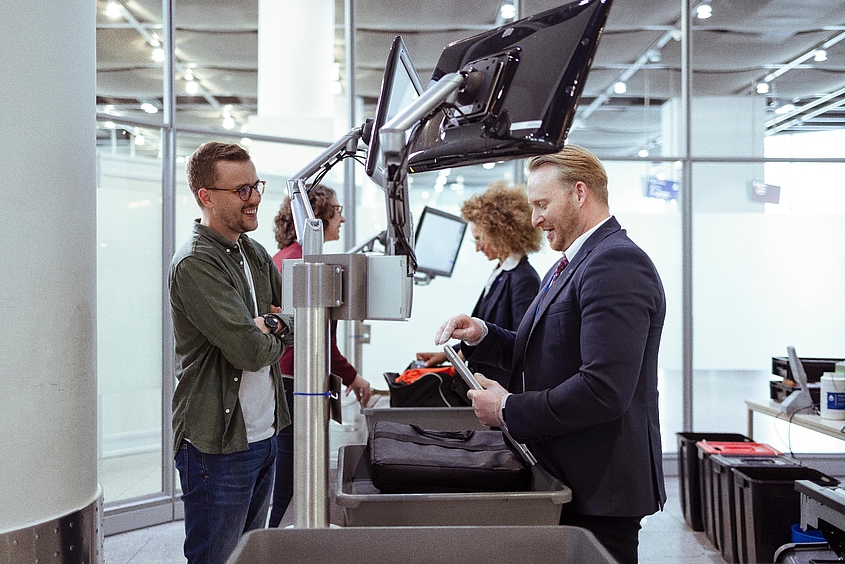Mitarbeiter vom DSW kontrolliert bei der Sicherheitskontrolle am Flughafen das Handgepäck