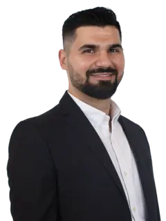 seitliches Portraitbild von Herrn Cigdemir mit dunklen Haaren, Bart, dunklem Sakko und weißem Hemd