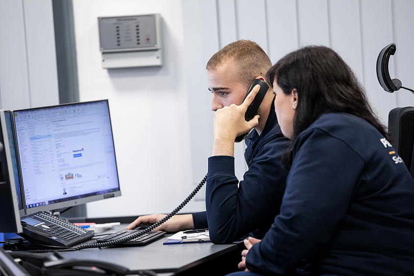 Definition Alarmverfolgung Piepenbrock-Mitarbeiter sitzen in Leitstelle