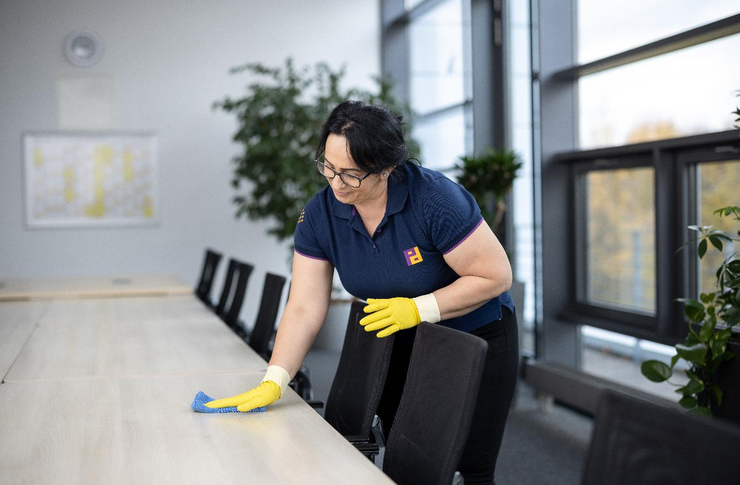 Frau wischt Bürotisch mit einem Lappen ab