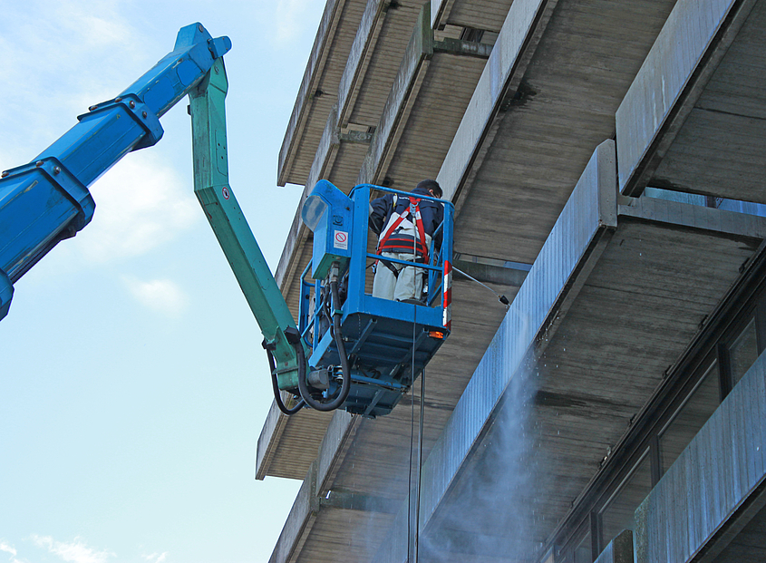 Definition von Klinkerreinigung Piepenbrock-Mitarbeiter reinigt Fassade mit Krank