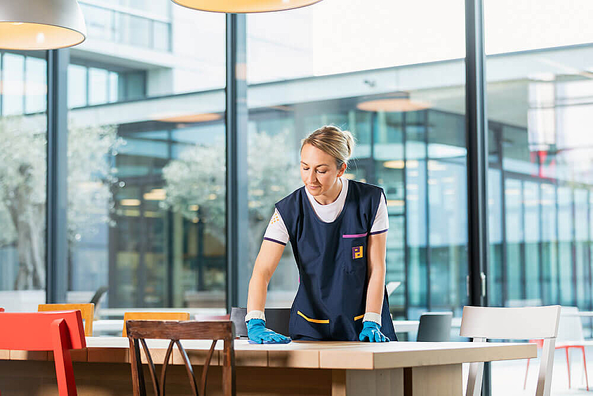 Grundreinigung von Tischen durch Mitarbeiterin von Piepenbrock
