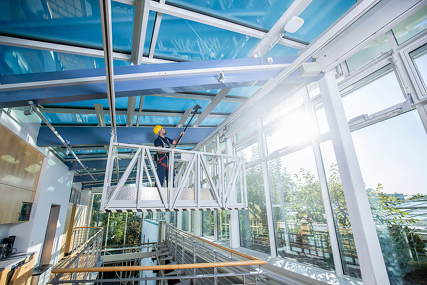Mitarbeiter der Glasreinigung säubert Glasdach 