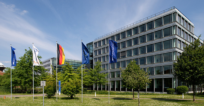 Diverse Flaggen vor einem großen Gebäude am Flughafen.